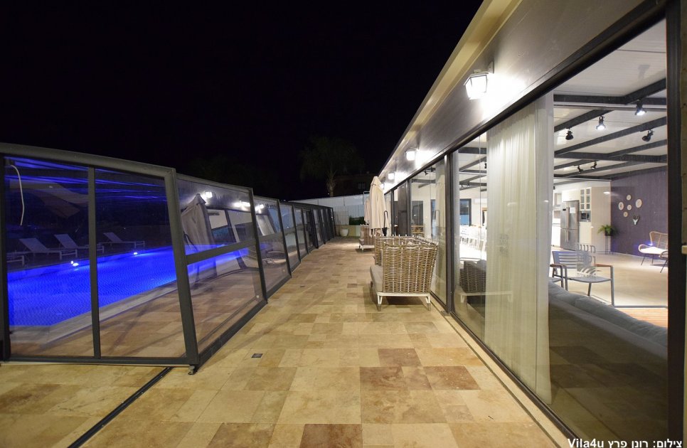 Stone terrace between the shared space and the covered pool at night
