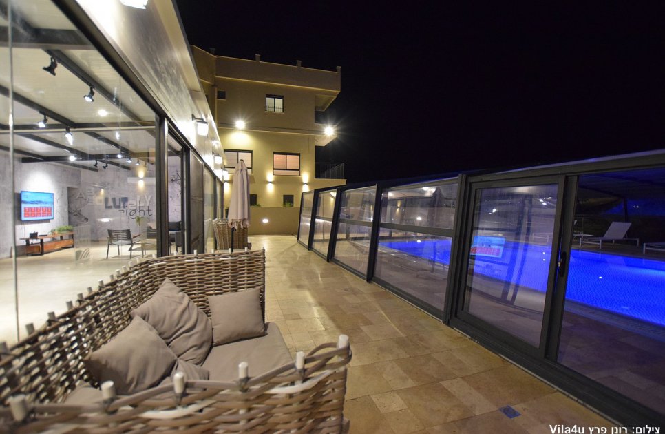 Wicker sofa on the terrace, the covered pool and the villa at night