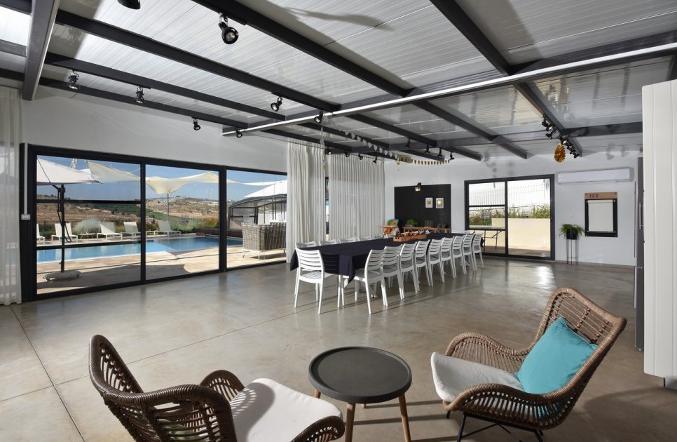 The shared space with a long table and glass doors onto the pool
