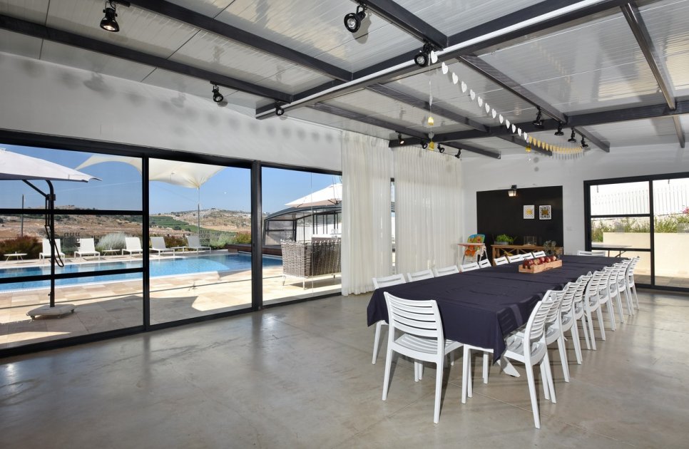 Long dining table in the shared space, looking out to the pool
